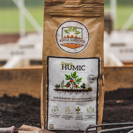 bag of simply humic next to garden trowel in garden soil