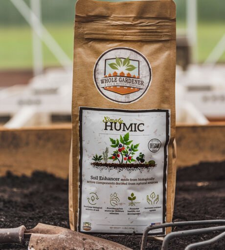 bag of simply humic next to garden trowel in garden soil